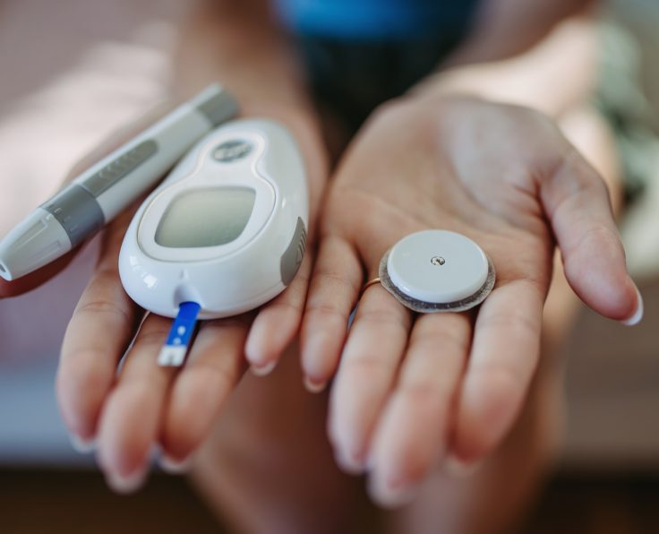 Close up of hands with diabetes supplies and devices.