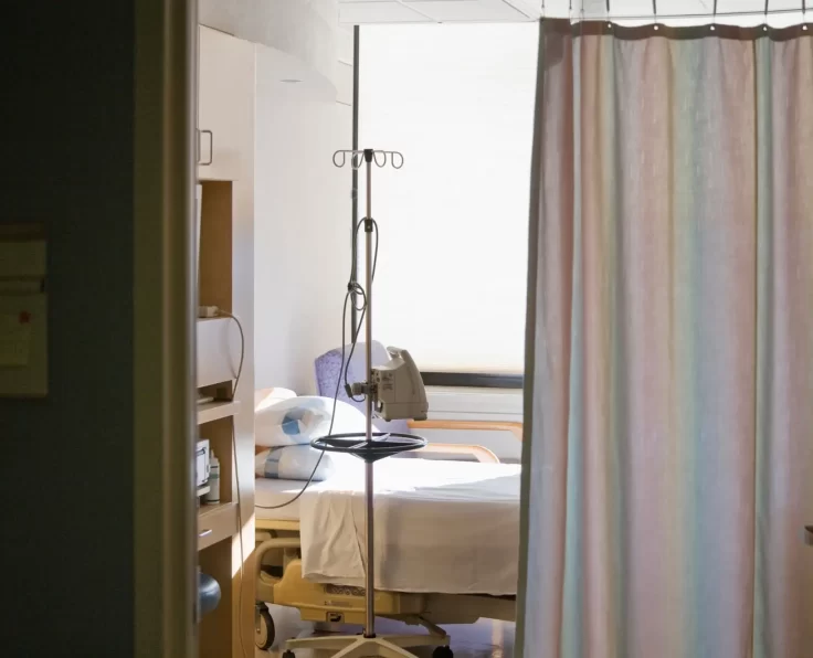 Hospital room with bed and privacy curtain.