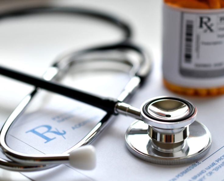 A doctor's stethoscope on a prescription RX pad with a bottle of medicine, pharmacy pharmaceuticals