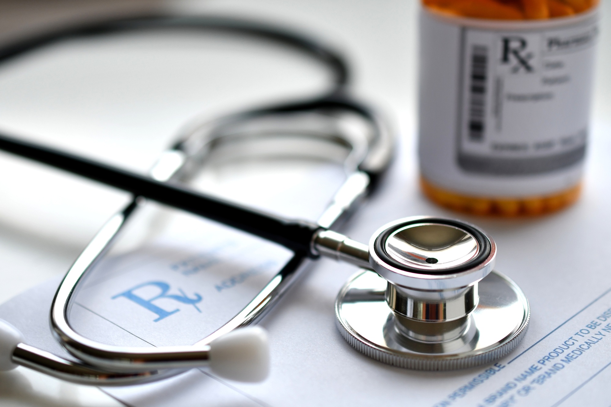 A doctor's stethoscope on a prescription RX pad with a bottle of medicine, pharmacy pharmaceuticals