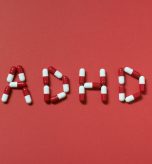 ADHD abbreviation formed of pharmaceutical pills on red background. Attention deficit hyperactivity disorder and mental health awareness.