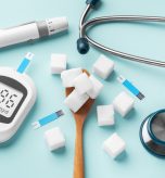 Sugar cubes in spoon with blood glucose meter, lancet and stethoscope on blue background