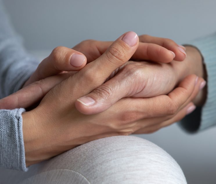 Close up young daughter comforting mature mother, granddaughter holding older grandmother hand, expressing love and support, good trusted family relationship, two generations, care to senior people