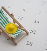 Green beach chair and hat on white blank calendar background copy space. Annual leave travel period for relaxation concept. Period of paid time off (PTO) granted to employees by their employer.